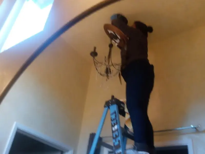 Electrician installing a chandelier in a Roseland residence